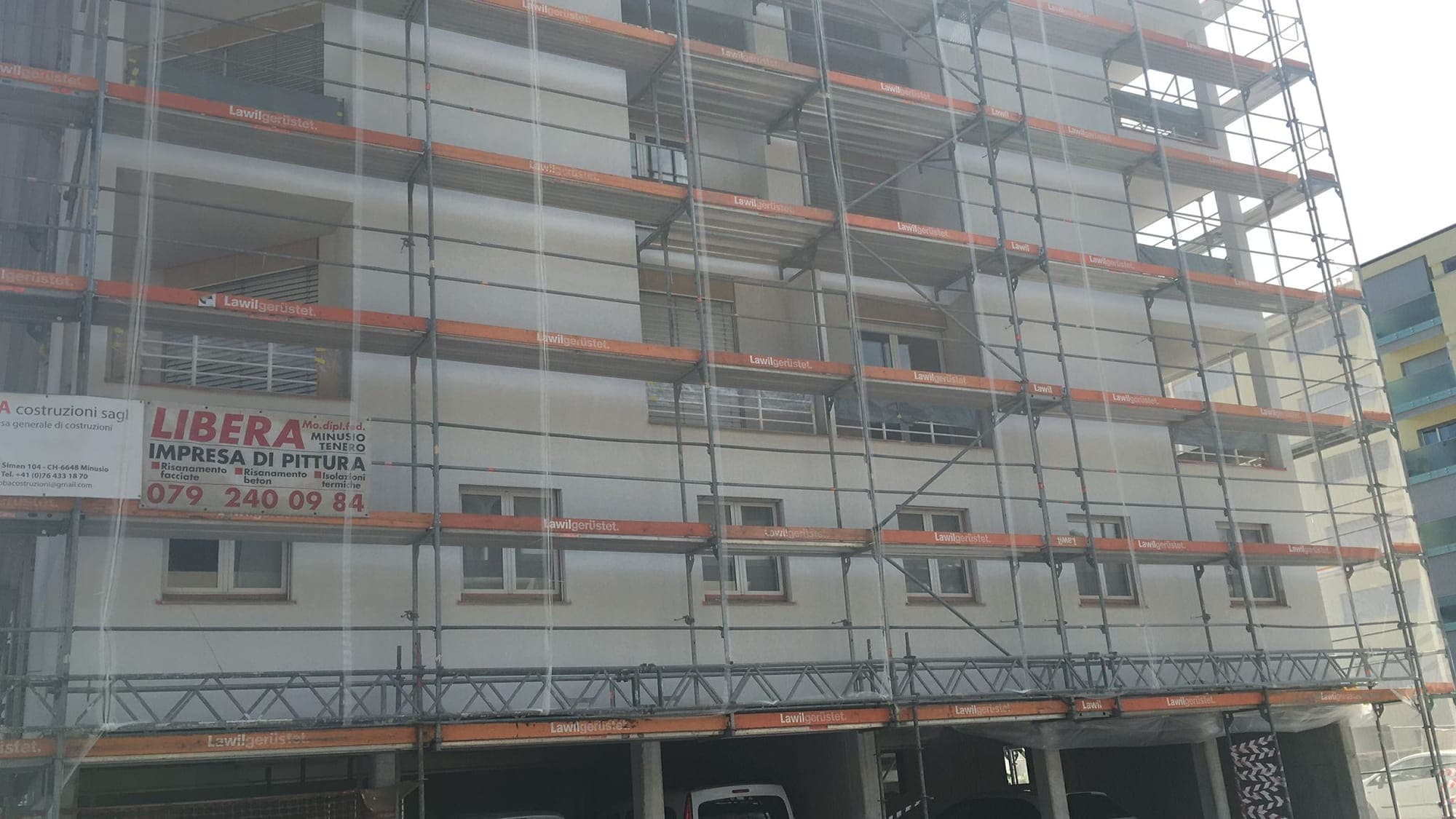Cantiere cappotto termico con ponteggi su palazzo in Ticino